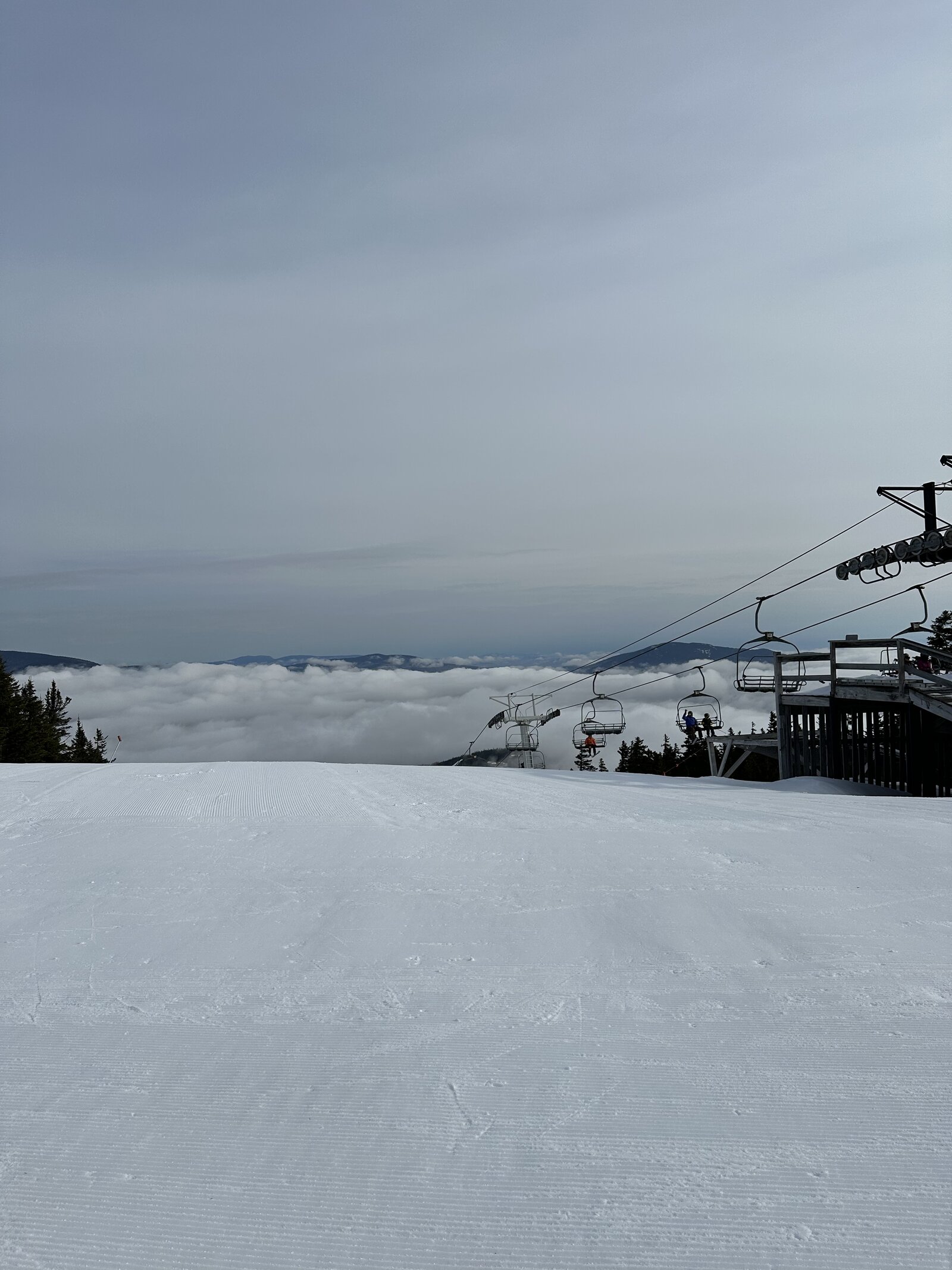 Empty chairlift rising above the clouds