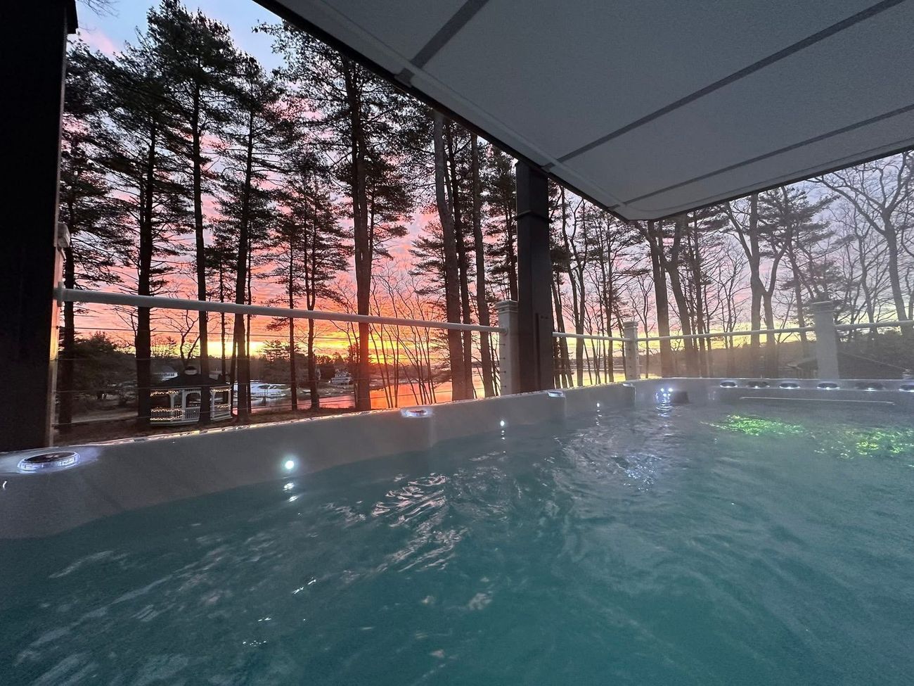 Hot tub view of a sunset over a lake through the trees