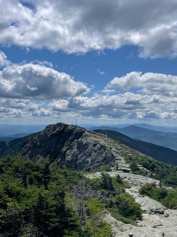 View from a rocky mountain summit under a partly cloudy sky